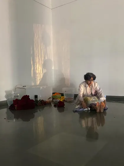 A still from Smitha Cariappa's performance, showing the artist's reflection in the gallery's polished floor, adding another layer to the visual experience.
