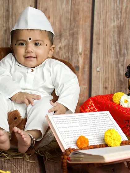Another sweet smile from our tiny Varkari. The setup includes a holy book and prayer beads, adding layers of authenticity and reverence to the portrait.