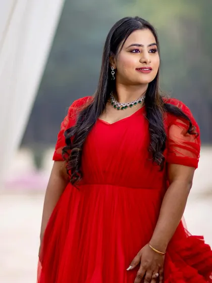 A smiling portrait of the bride-to-be in her red gown. The makeup is radiant and joyful, perfectly capturing her happiness.