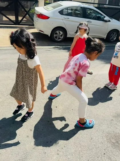 Children chase and play with their shadows on the street, turning a science lesson into an active game.