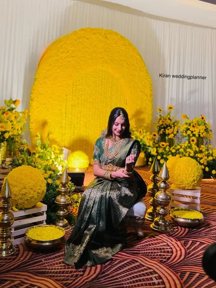 A full view of the sophisticated Haldi setup with the large circular marigold backdrop, showing the complete seating area for the bride.
