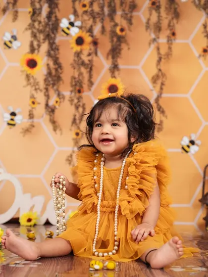 Dressed in a beautiful yellow tulle dress, this little girl is playing with pearls in our sweet honeybee theme.