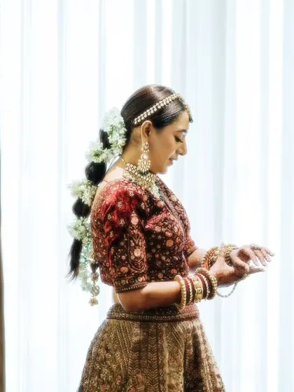 A side profile of a bride getting ready, showcasing her intricate hairstyle with fresh flowers. We pay attention to every beautiful detail.