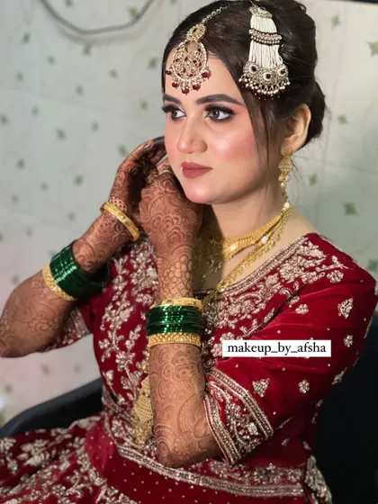 A candid moment as the bride adjusts her earring. This shot highlights the intricate jewellery and the beautiful henna design.