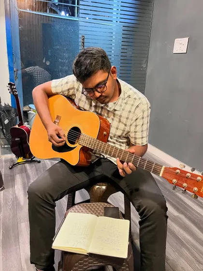 A student works through his lesson book during a guitar class. We combine practical playing with essential music theory to create well-rounded musicians.