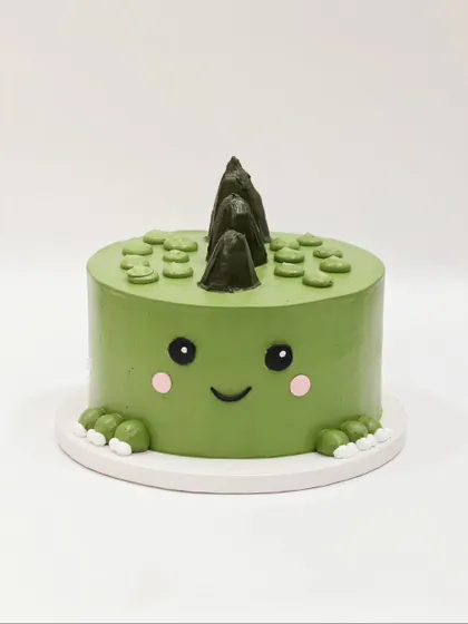 A cute and minimalist dinosaur cake, with a friendly dino face peeking out.