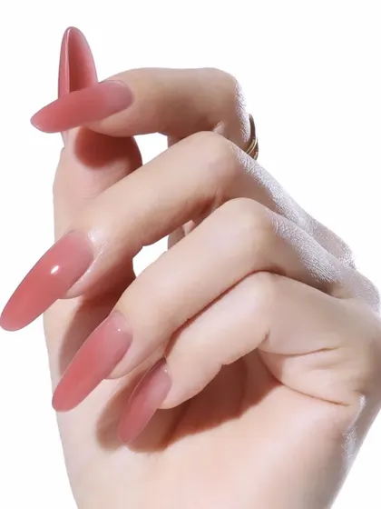 A beautiful, translucent jelly polish in a dusty rose color on long stiletto nails for a unique and trendy look.