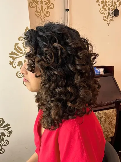 The side profile of Hinshara's medium-length curly cut.