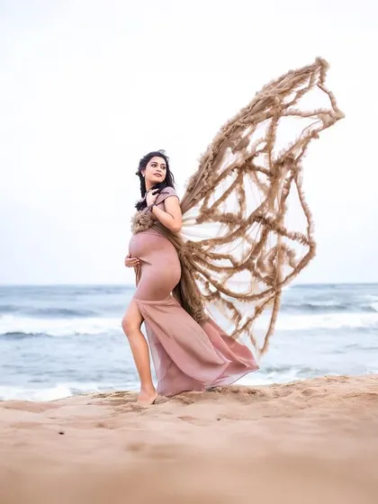 This beige gown with unique, net-like wings creates an artistic and earthy look, perfect for a creative beach maternity portrait.