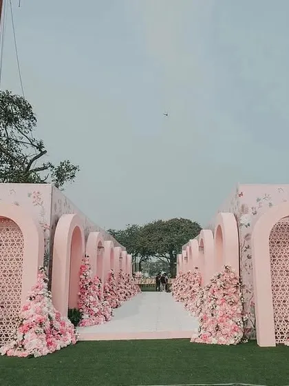 A wide view of the magnificent entrance for Yasha and Rahil's blush wedding. The series of pink arches and floral arrangements created a dramatic and immersive experience, leading guests to the seaside ceremony.
