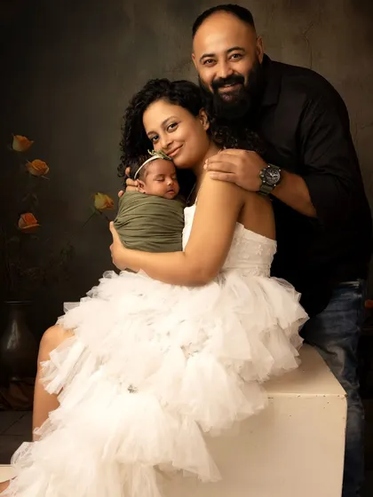 A classic family portrait with a newborn. The parents cradle their new baby, creating a timeless image of a new family of three.