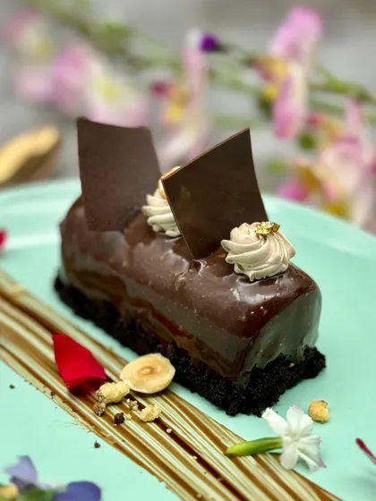 A final, perfect look at our Ferrero Rocher Entremet. The glossy glaze, piped topping, and scattered hazelnuts make it an irresistible centrepiece of any dessert table.