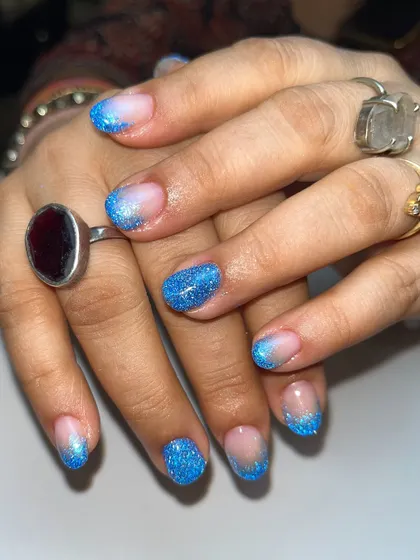 The full view of the blue glitter ombre nails. The way the light hits the reflective glitter makes them sparkle from every angle.