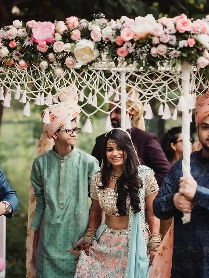 The bride's entrance under a unique macrame and pastel floral phoolon ki chadar, a modern take on a beautiful tradition that we loved creating.
