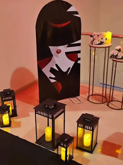 Setting the mood with elegant decor elements. This setup includes tall pedestals with floral arrangements, candle-lit lanterns, and a stylish art deco-style cutout.