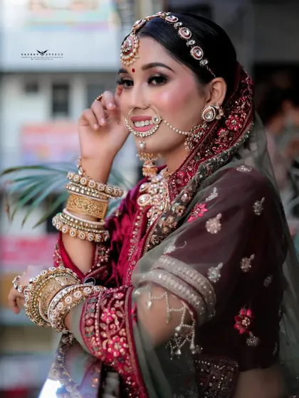 A smiling portrait of the bride looking towards the camera. This shot captures her happiness and the stunning details of her bridal attire, including the matha patti and nath.