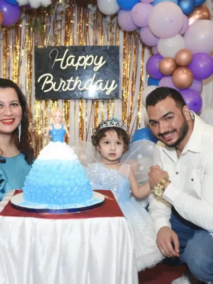 A classic family photo by the birthday cake. Everyone is smiling, ready to celebrate the little one's big day.