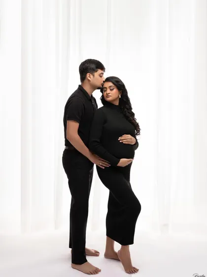 A classic couple's portrait in matching black outfits. His kiss on her forehead is a timeless gesture of love and protection.