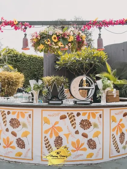 The bar for the Haldi ceremony, with a custom-printed front featuring autumn leaves and pinecones, topped with a beautiful floral arrangement. It's a perfect blend of rustic and festive.