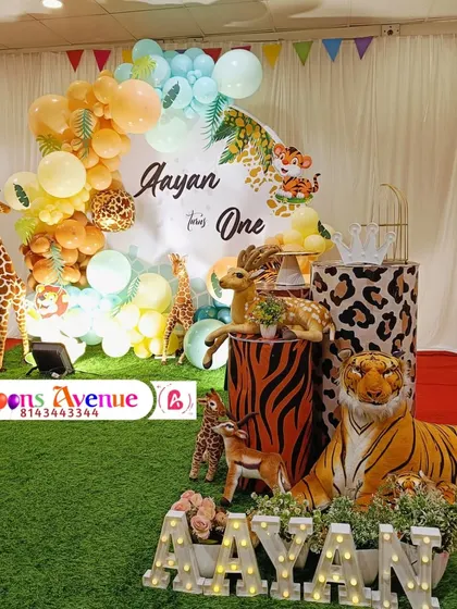 A full view of the jungle party stage, including the light-up name 'AAYAN' and the collection of animal props.