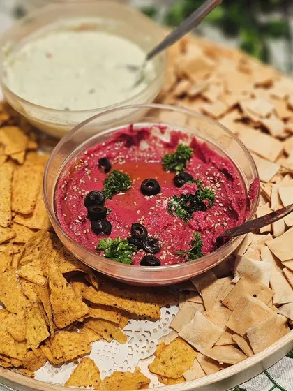 A delicious platter of hummus, beetroot dip, and other spreads served with pita bread and nachos. A perfect Mediterranean-inspired addition to any grazing table.