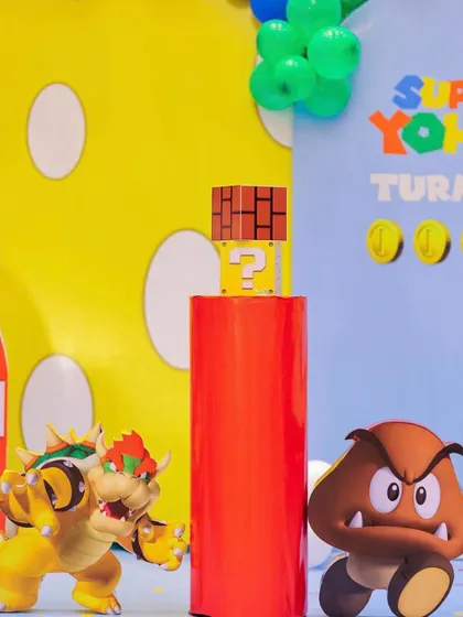 A close-up of the Super Mario party decor, featuring Bowser and a Goomba next to a red warp pipe and a question block. The character cutouts are high-quality and bring the scene to life.