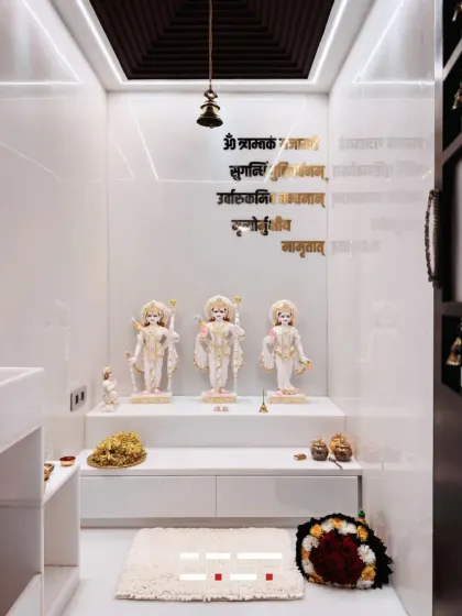 A wider view of the white marble mandir, showing its clean lines and the peaceful ambiance created by the focused lighting. The space is designed to be a corner of calm and positivity.