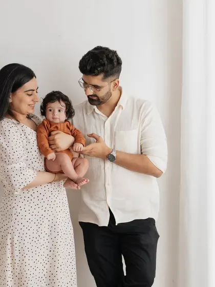 A classic family pose with a modern, minimalist feel. The parents' interaction with their baby makes this a warm and engaging portrait.