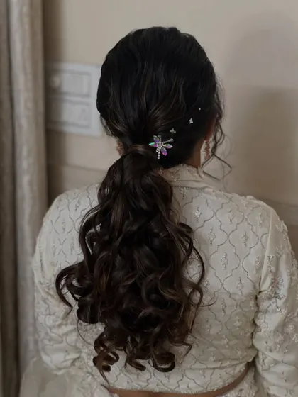 A modern and stylish ponytail with soft waves and a unique dragonfly accessory. This hairstyle is perfect for the bride who wants something a little different.