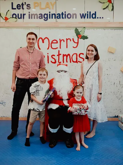 A family smiles for the camera with Santa and their presents.
