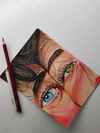 A finished piece showing two different colored eyes, one blue and one green. This was a study in how to render different eye colors realistically using colored pencils.