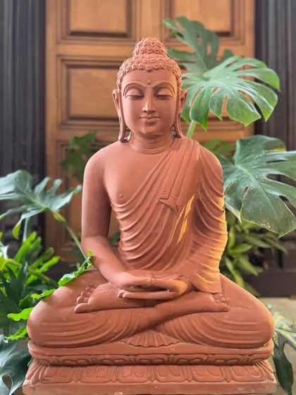 The red sandstone Buddha in meditation, a beautiful handcrafted statue that brings stillness and divine energy to your garden.