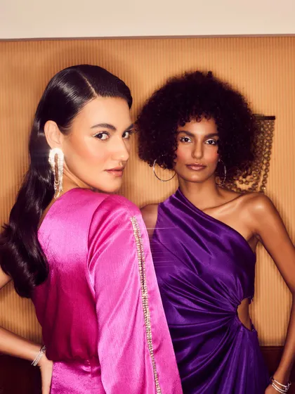 A close-up of the two models, highlighting the makeup and jewelry styling. The models' confident expressions and direct eye contact create an engaging and aspirational image.