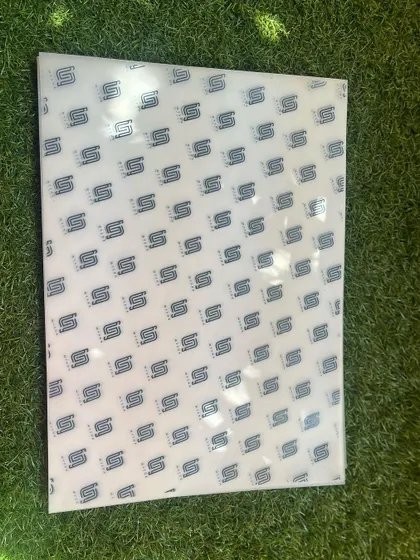 A full sheet of the custom-branded wrapping paper, laid out on a grassy background to show the design clearly.