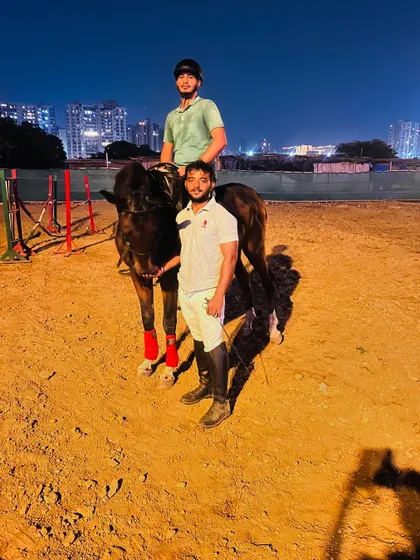 A rider and trainer stand with their horse after a successful evening training session.