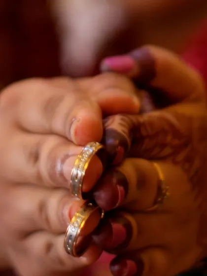 A close-up of a couple's hands, showing their wedding rings.