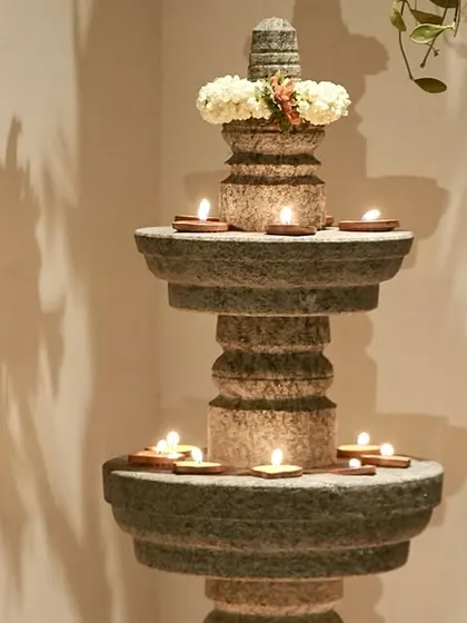 A multi-tiered stone lamp, lit with diyas for our Navaratri celebration. This handcrafted piece adds a touch of traditional grace and warm light to any corner, creating an enchanting atmosphere.
