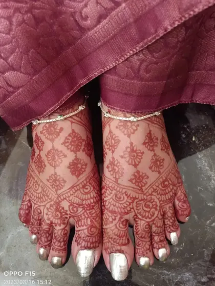 A duplicate image of the rich henna stain on the feet, adorned with silver toe rings and anklets.