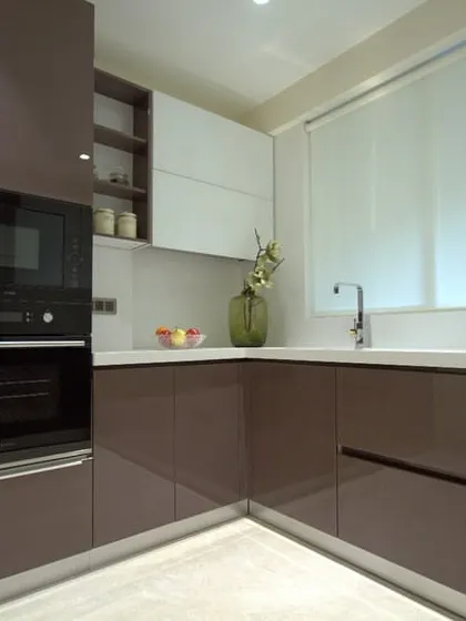 A classic and practical modular kitchen from our Bellevue Apartment project. The glossy brown and white cabinets provide a sleek look, while the U-shaped layout maximizes counter and storage space.