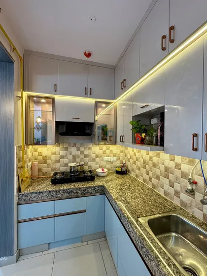A corner view of a completed kitchen. The combination of light blue and grey cabinets with a patterned tile backsplash gives it a unique and personalized feel.