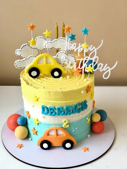 A cute and colorful car-themed cake for a second birthday, with a yellow and blue ombre design.