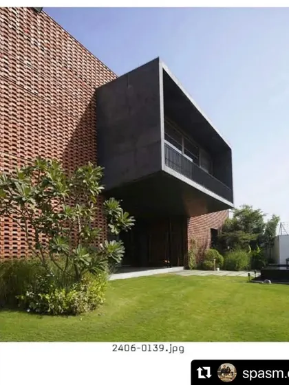 The Ishtika house seen from its garden. We designed a simple, open lawn to contrast with the complex, textured facade of the building, allowing the architecture to take center stage.