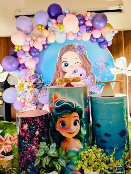 A detailed shot of the central part of the mermaid decoration, with the cake stands and character backdrop.