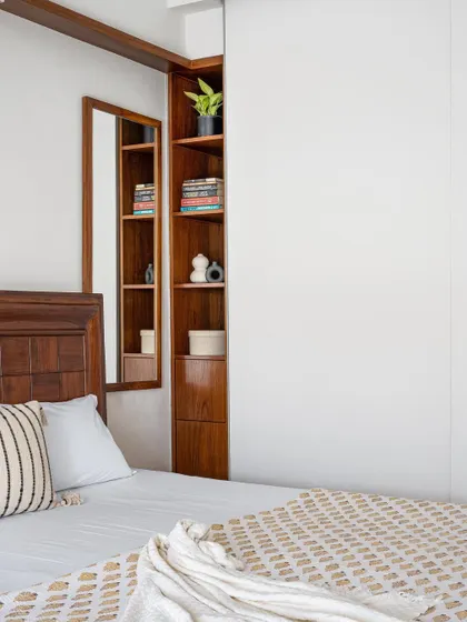 A clever storage solution in the 'Gulmohar' primary room, with a mirrored niche that opens to reveal hidden shelving, blending functionality with elegant design.