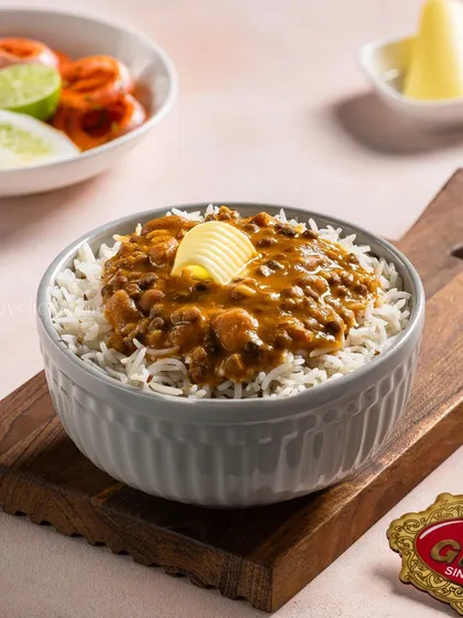 A simple yet satisfying bowl of Dal Makhani over rice, topped with a pat of butter, perfect for a quick meal menu.