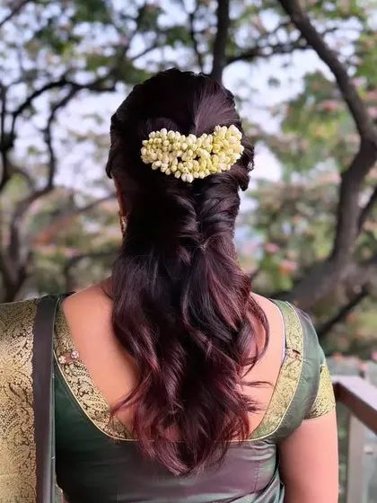 A half-up fishtail braid with a jasmine gajra, combining modern braiding with a traditional floral touch.
