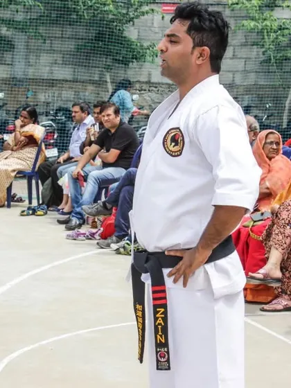 Me observing my students during a belt exam, with parents watching in the background. I ensure that every detail of their performance meets our high standards.