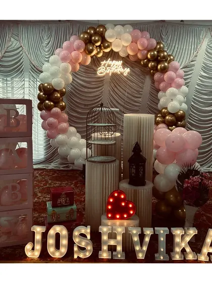 An elegant birthday setup with a circular balloon arch in pink, white, and gold, complete with the birthday girl's name in marquee letters.