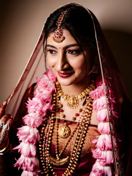 A beautiful shot of the bride, her face framed by her veil. The makeup is soft and romantic, with a focus on her glowing skin.