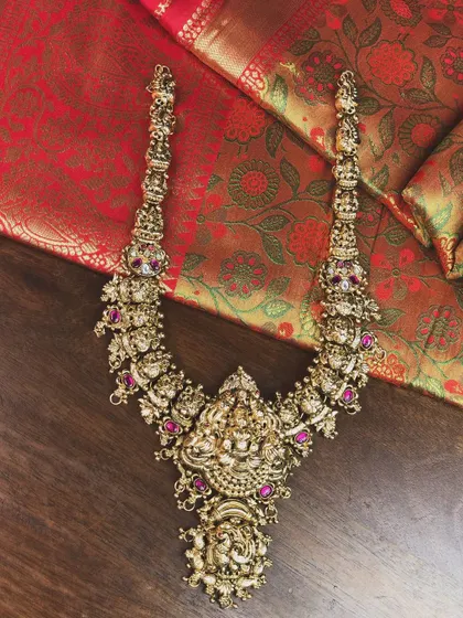 A magnificent long temple haram with intricate carvings and ruby accents. This is a true statement piece for a bride.